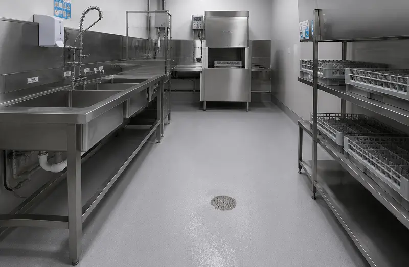 Heat-welded vinyl sheet flooring in a UAE restaurant dish pit and washing-up zone with sealed floor drain